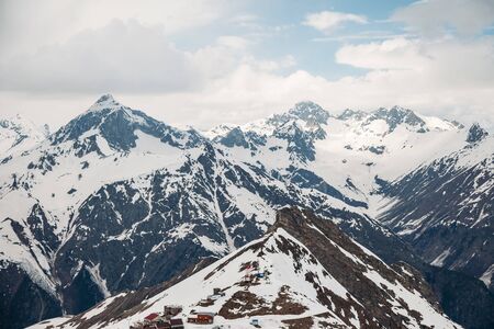 The views of the high snow-capped mountain peaks are covered with fluffy white clouds