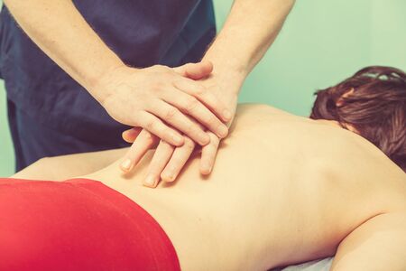Chiropractor making treatment procedures. Young woman relaxing on massaging table, masseur working with her back. Beauty, health, rest, spa, body concept の写真素材