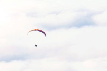 Paraglider flies on the background of clouds on a sunny day/ copy spaceの写真素材