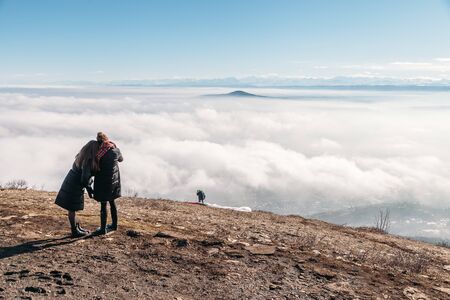 people on top of the mountain take pictures of paraglidersの写真素材