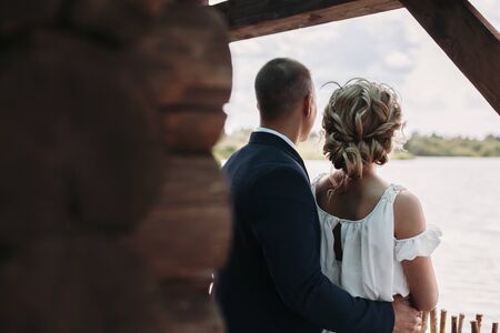 bride and groom in a country house looking into the distance on the lakeの写真素材