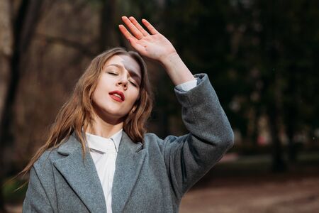 Portrait of a young girl businesswoman in a grey coat posing in Park in autumnの写真素材