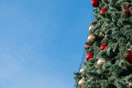 Closeup of beautiful decorated christmas tree outdoors against the sky. Holiday background