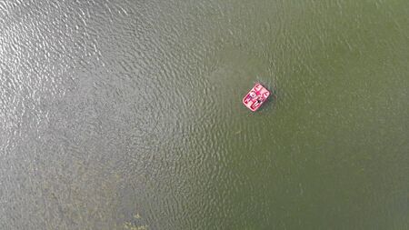 4k Aerial top down view of people on the red sail catamaran on lake on Sunny day.