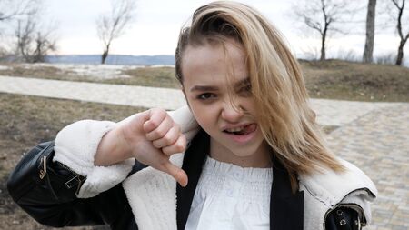 European woman shows disapproval sign, gives thumb down gesture, dislikes something, has disgusting...