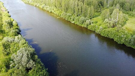 4K aerial stock footage of river located among forest in summer at sunset.