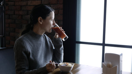 Young beautiful woman eating in a cafe, healthy food, salad and juiceの写真素材