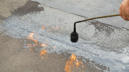 Working with a gas burner melts the tar up on the roof for future roof repairs.