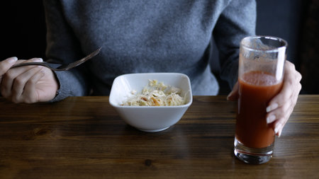 Beautiful young happy woman sitting at the table in cafe and enjoying the meal. Attractive hungry woman eating tasty lunchの写真素材