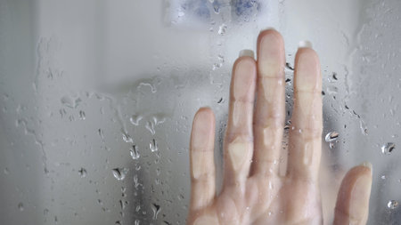 Unrecognizable woman touches glass while takes shower palm on sweaty in shower.