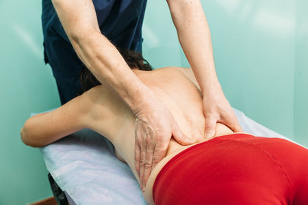 chiropractor massaging back of patient that lying on massage table in hospitalの写真素材