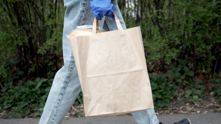 Young woman in latex gloves contactless delivers package with products, goods to client during quarantine period. food.の写真素材