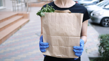 Courier, delivery man in protective mask and medical gloves delivers takeaway food. Delivery service...