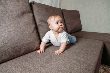 hildhood babyhood and people concept happy smiling little baby boy or girl crawling on sofaの写真素材