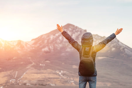 hiker on top mountains with arms raised in air. view from backの写真素材