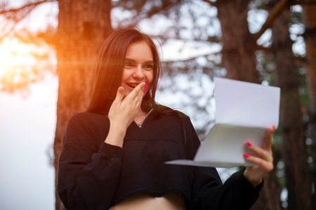 young beautiful woman reads a paper letter and enjoys the good news.