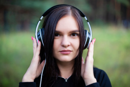 close-up portrait of young woman with headphones on her ears looking at camera.の写真素材