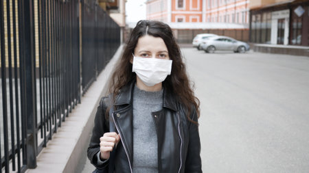 Close up portrait of caucasian brunette in protective medical mask on her face. epidemic of influenza virus and coronavirus is everywhere.の写真素材