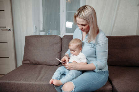 mother and baby are looking to play tablet computer or smart phone at home.