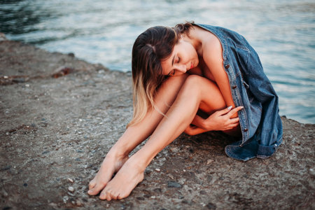 sad young woman sitting by the sea.の写真素材