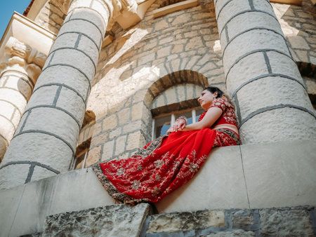 Beautiful ethnic Indian Saree. Young woman in red, colorful, sensual, wedding and very feminine outfit - Indian sari poses on old streets in India. Traditional national clothing of Indian women.の写真素材