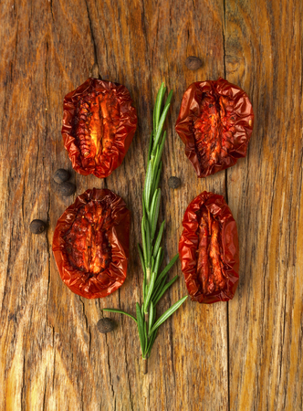 Delicious Dried Tomatoes, a branch of rosemary in a Rustic style, on wood backgroundの写真素材