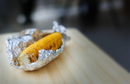 Baked yellow corn in foil on white backgroundの写真素材