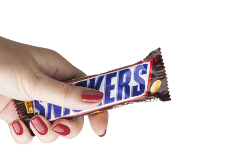 CHISINAU, MOLDOVA - December 21, 2017: Hand holding a Snickers chocolate bar. Snickers bars are produced by Mars Incorporated. Snickers was created by Franklin Clarence Mars in 1930のeditorial素材