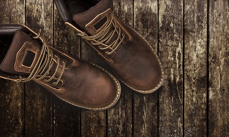Brown men's boots, on a wooden background. Closeup isolated