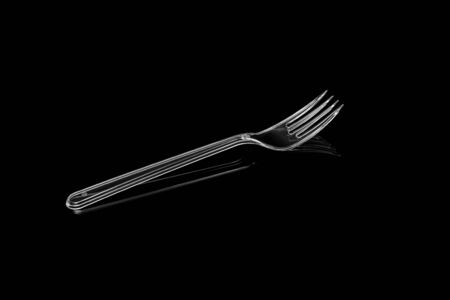 Transparent plastic fork isolated on black background.