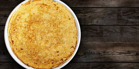 Homemade pancakes on a white plate on a wooden plank. Pancake week. Delicious breakfast. View from the top.の写真素材