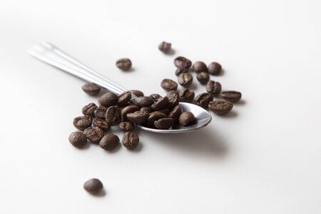 Spoon with coffee beans, macro photo. Isolated on white backgroundの写真素材