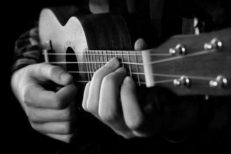 A young man playing ukulele. Black and white photography.