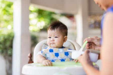 the baby learns to eat by himself. he can use spoon well. so he is very happy (focus at his face)の写真素材