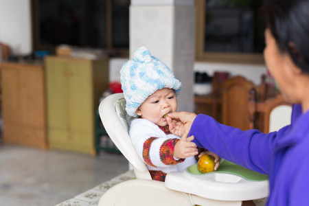 the baby learns to eat by himself. he can use spoon well. so he is very happy (focus at his face)