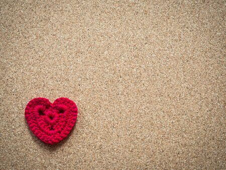 Red crocheted heart on cork board.の写真素材
