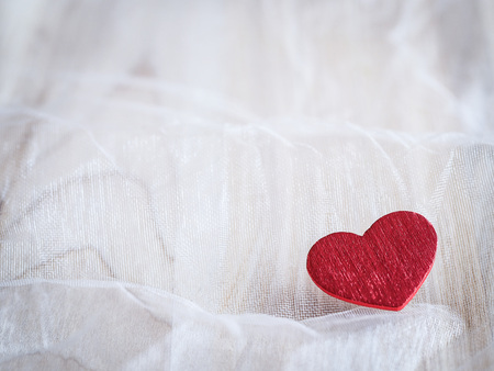 Red heart on a soft white textile backgroundの写真素材