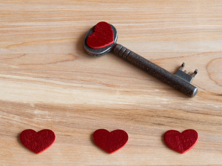 Old key and red hearts on a wooden background