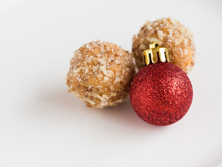 Detail of tasty homemade walnut balls on white plate with flashy glitter and shiny red christmas ornamentの写真素材