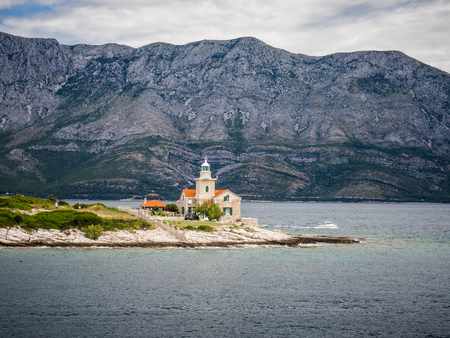 Ferry passing close to Sucuraj lighthouse on Hvar island on a sunny summer day, Croatia