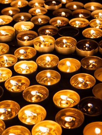 Group of lighted tea candles in church on Christmas, black backgroundの写真素材
