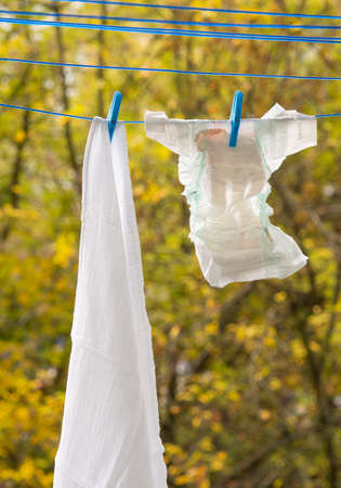 Baby diapers hanging on a clothesline, paper diaper and cotton diaper with clothes pinの写真素材