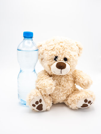 Cute fluffy teddy bear with water in plastic bottle - children stuffed toy on white backgroundの写真素材