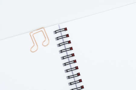 Close up of paper clip in shape of note on blank spiral notebook isolated on white backgroundの写真素材