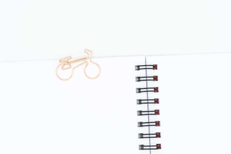 Close up of paper clip in shape of bike on blank spiral notebook isolated on white backgroundの写真素材