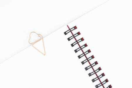 Close up of paper clip in shape of ice cream on blank spiral notebook isolated on white backgroundの写真素材