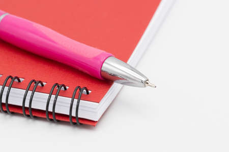 Spiral notebook or notepad with red cover and pink pen isolated on white backgroundの写真素材