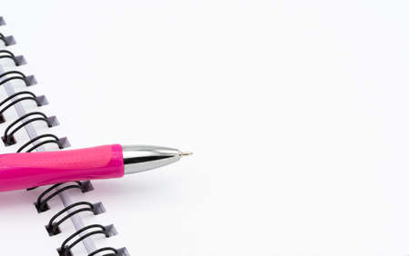 Open blank spiral notebook with pink pen isolated on white backgroundの写真素材