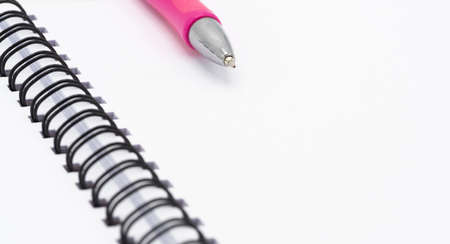 Open blank spiral notebook with pink pen isolated on white backgroundの写真素材