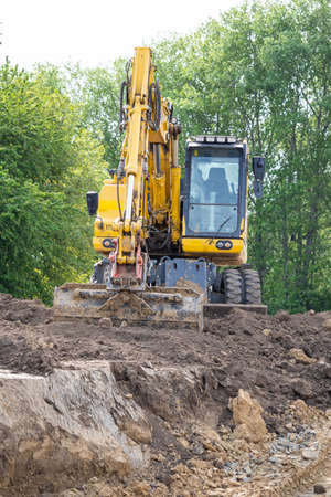 Yellow excavator in construction site digging soil